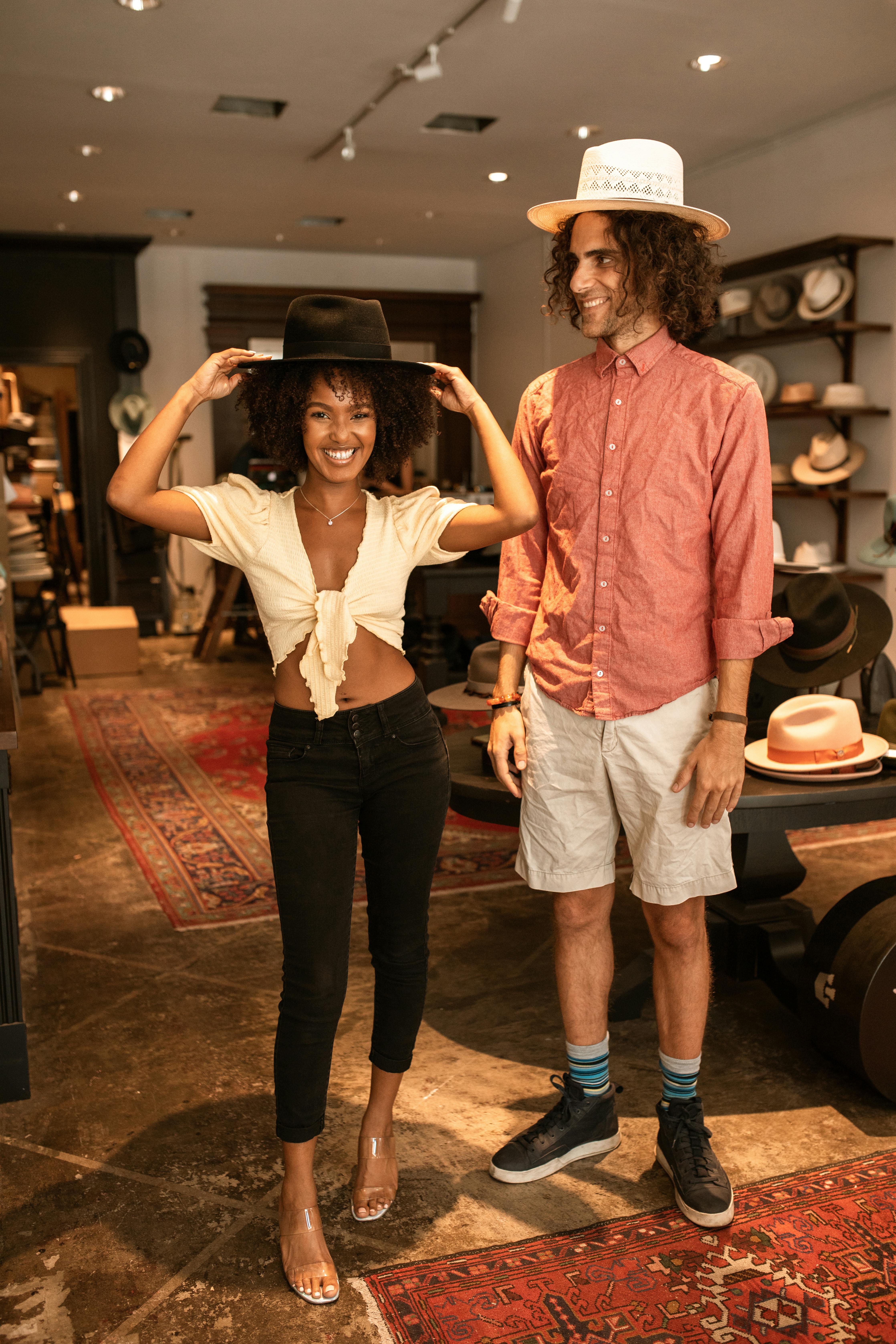 a man and woman standing while wearing a hat