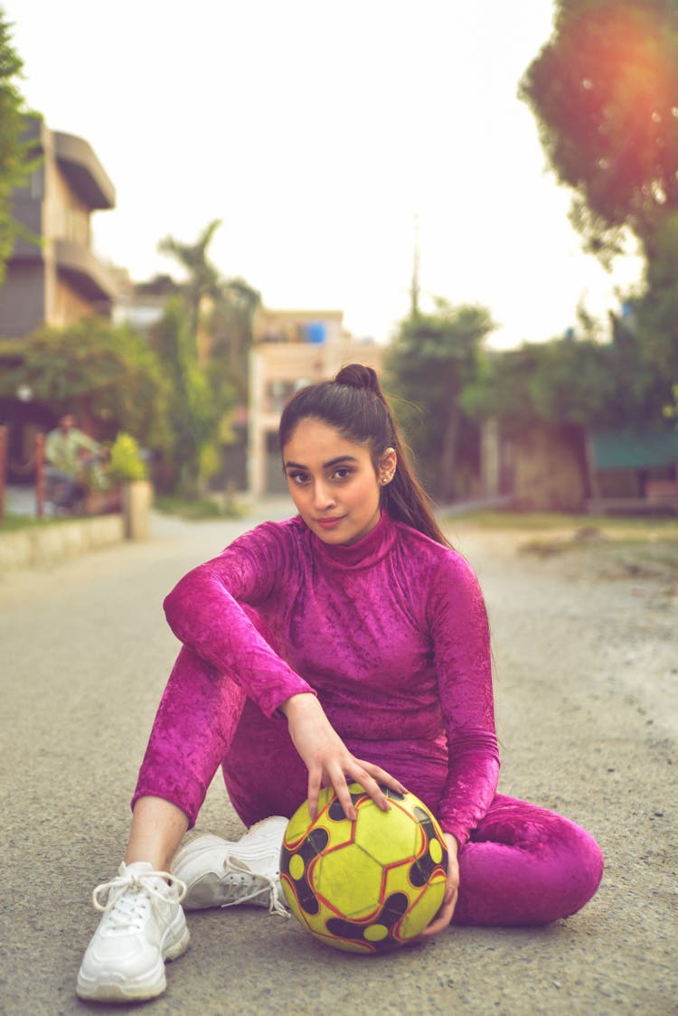 Woman Sitting On Street With Football Ball