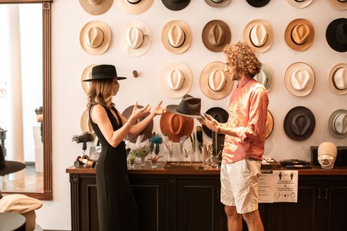Free A fashionable hat boutique with a male and female customer discussing styles indoors. Stock Photo