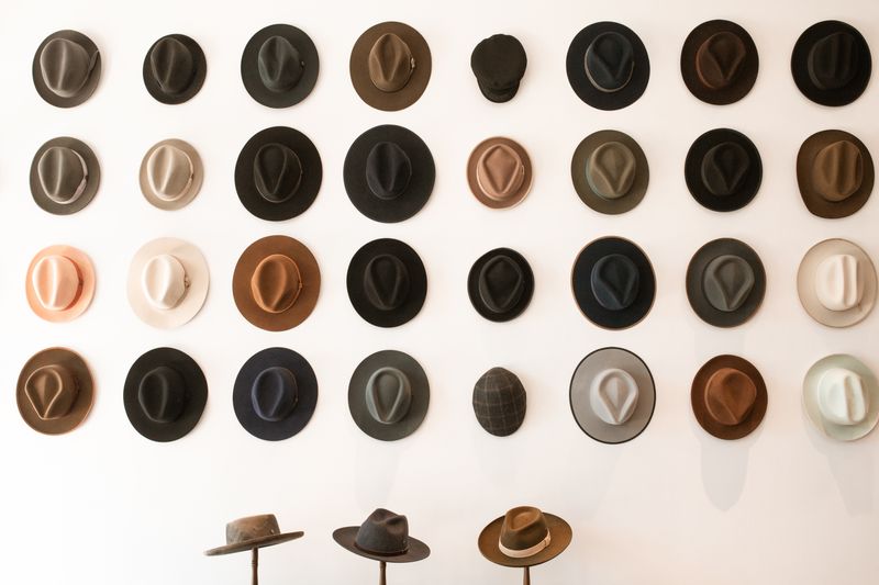 A row of finished hats on a pale display wall &mdash; photo by RDNE Stock project on Pexels