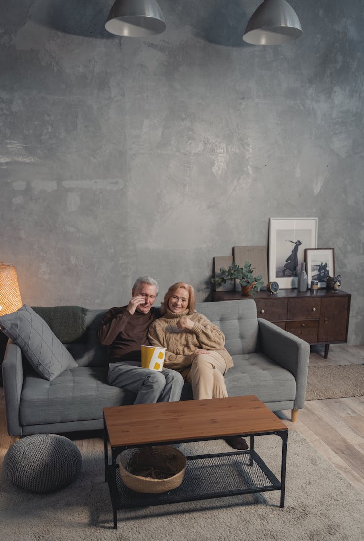 A Couple Sitting On A Gray Couch