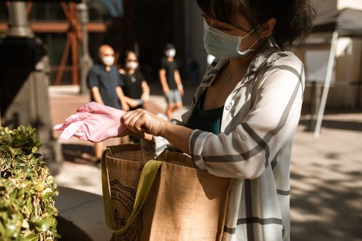 女人戴着口罩和手套在户外购物，强调健康预防措施