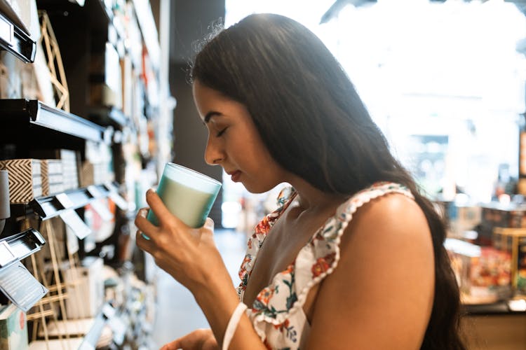 Brunette Woman Smelling A Scented Candle In Glass