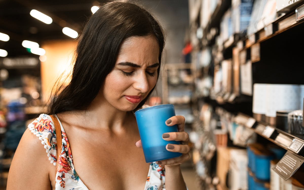 A young woman in a floral dress experiences an unpleasant scent while shopping.