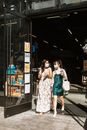 阳光明媚的日子里，两名戴着口罩的妇女购物后离开了商店