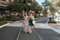 两个戴着口罩的女人在阳光明媚的城市街道上散步购物