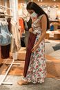 Woman in Floral Dress Holding Maroon Leggings on Hanger