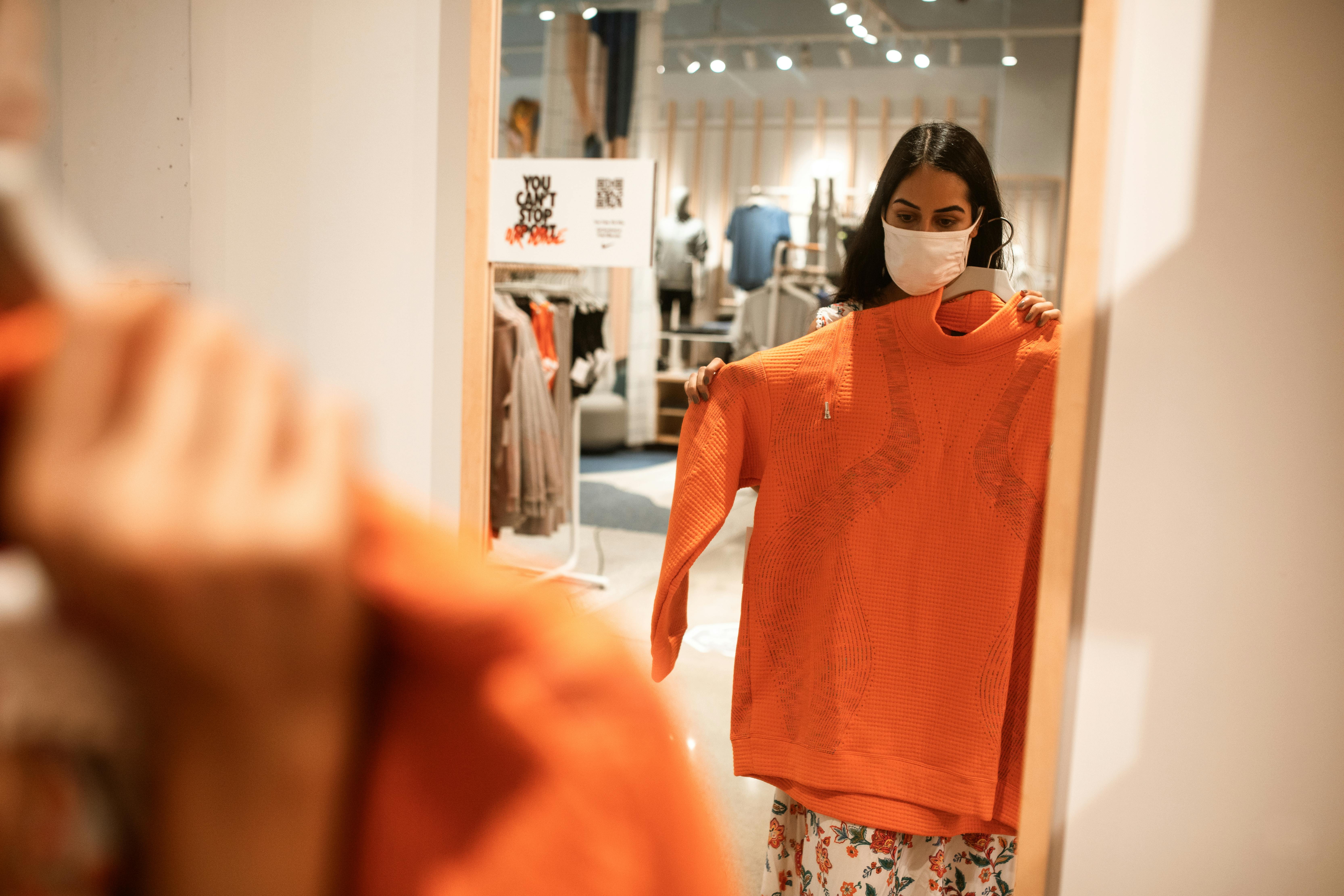 woman standing in front of a mirror checking on an orange long sleeve shirt