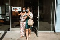 两名戴着口罩的妇女离开了那个充满活力的购物区的商店