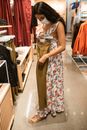 大流行期间，一名戴着口罩、身穿花裙的女子在一家商店里购买棕色裤子