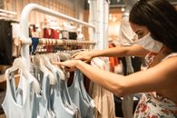 一名女子戴着口罩在商店买衣服，这反映了疫情下的新常态