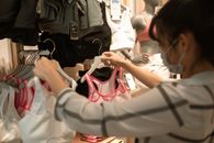 一名女子戴着口罩在商店购买运动胸罩，展现了新的日常购物体验