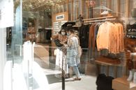 两名妇女戴着口罩，在一家时尚精品店购物，采取了疫情预防措施