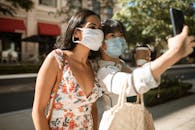 阳光明媚的购物日，两名戴着口罩的女子在自拍