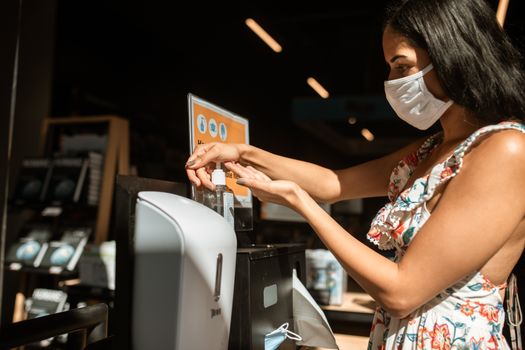 一名妇女在公共场所使用洗手液分配器，强调卫生和安全