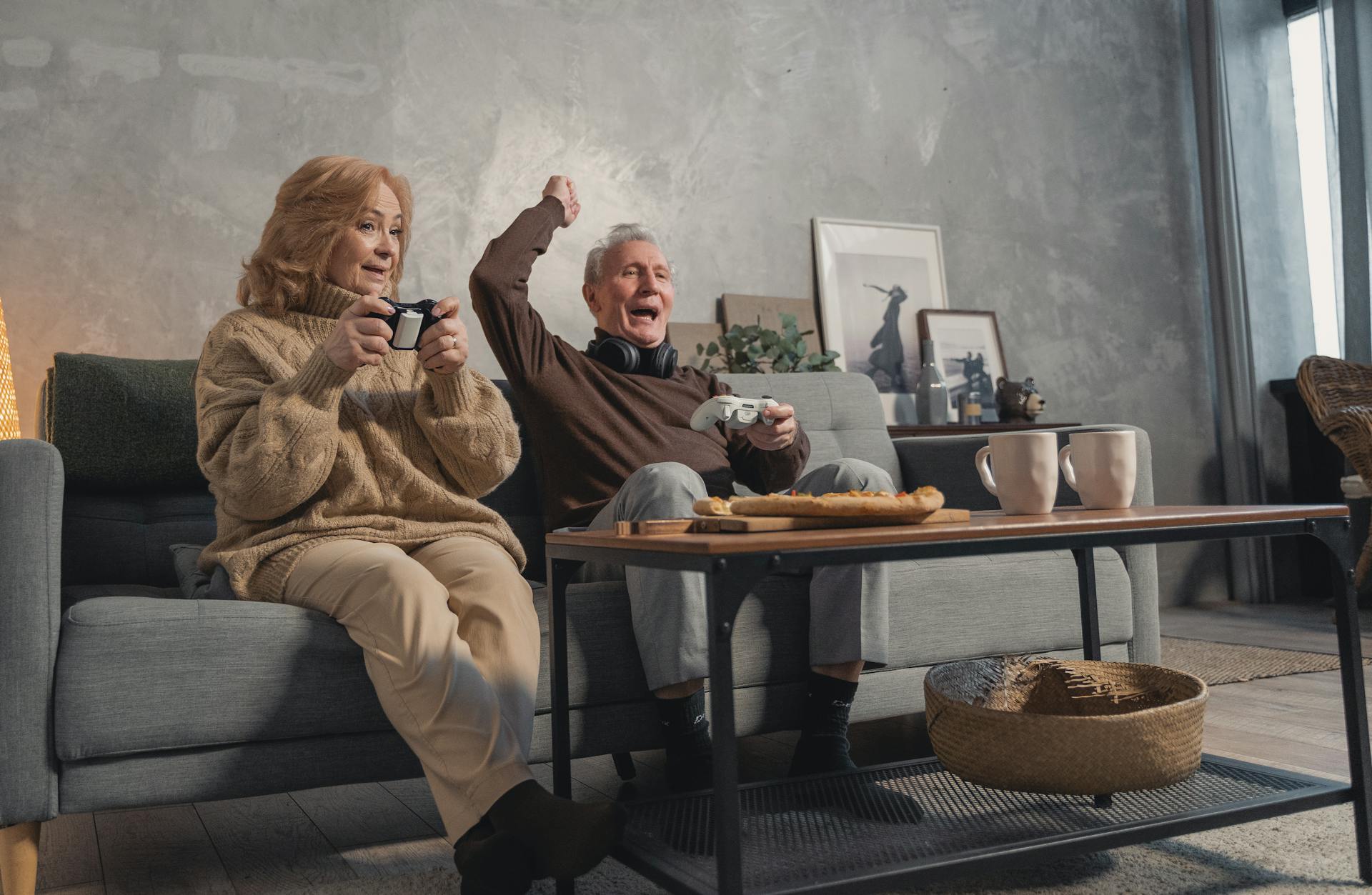 Happy senior couple enjoying video games and coffee in their cozy living room.