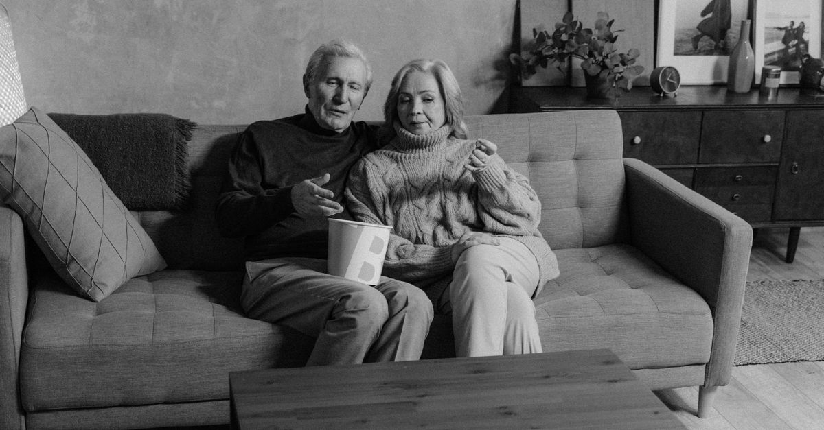 A serene moment of an elderly couple relaxing together on a sofa in a monochrome setting.