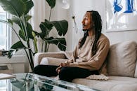 Side view of African American male client sitting on couch and speaking during consulting therapy in modern office with green plant