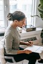 Focused ethnic woman writing on clipboard