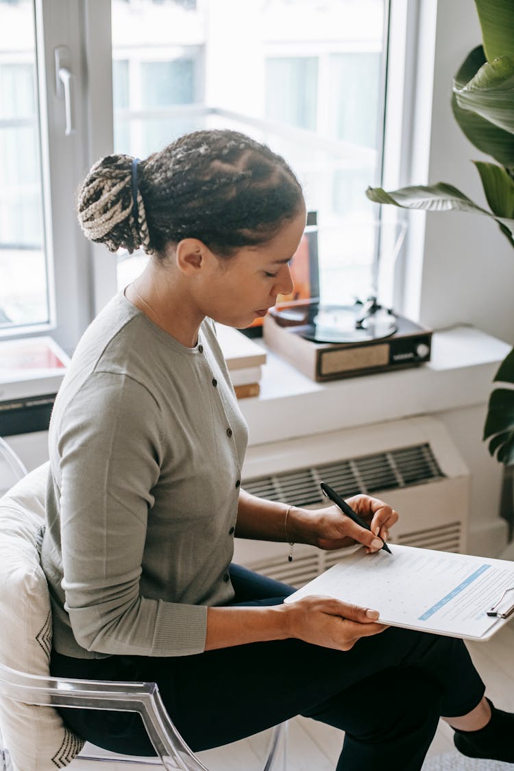 Focused Ethnic Woman Writing On Clipboard