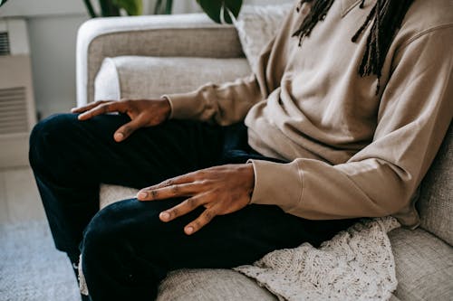 Crop ethnic man sitting on sofa