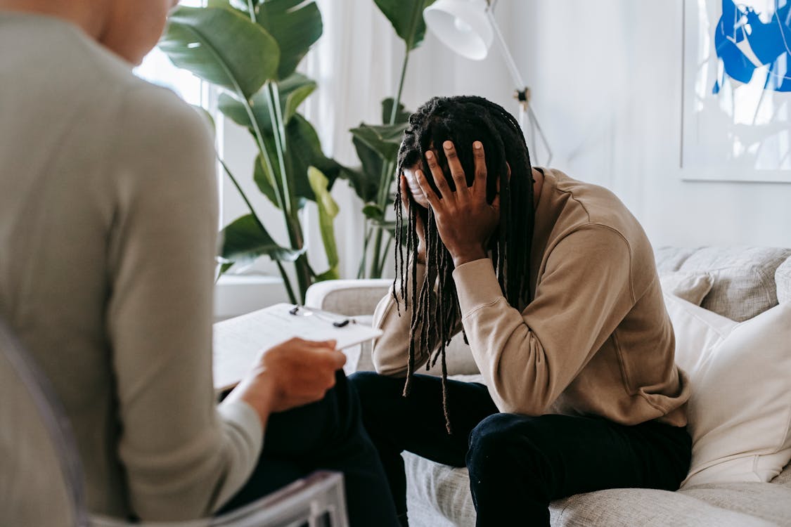 Stressed black man with dreadlocks in psychological office