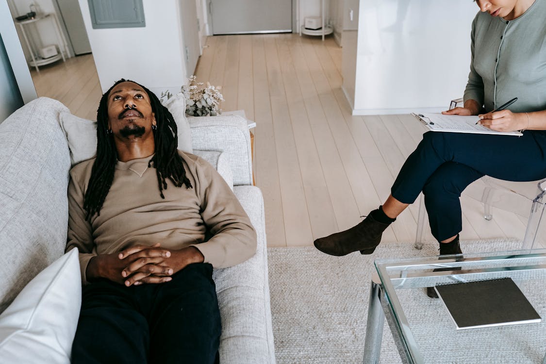 Free Black man lying on sofa in psychological office Stock Photo