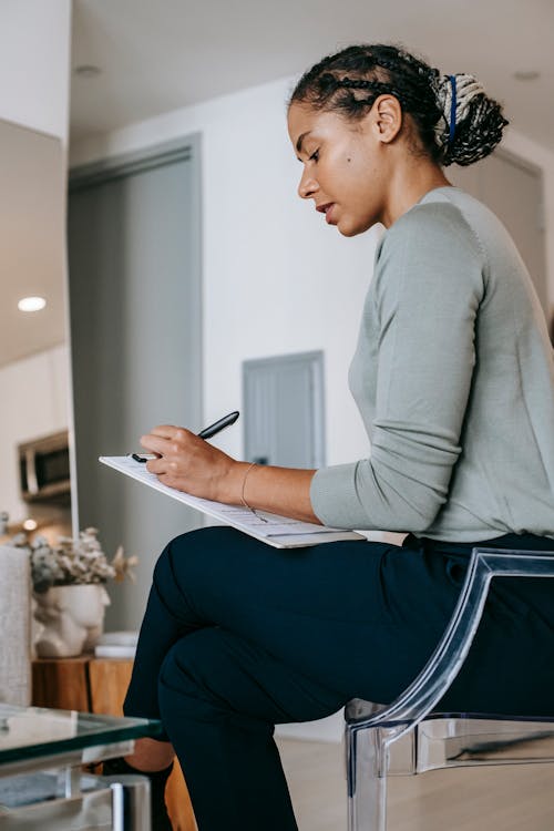 Serious black woman taking notes in living room