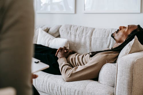 Crop black man lying on sofa in psychotherapist office