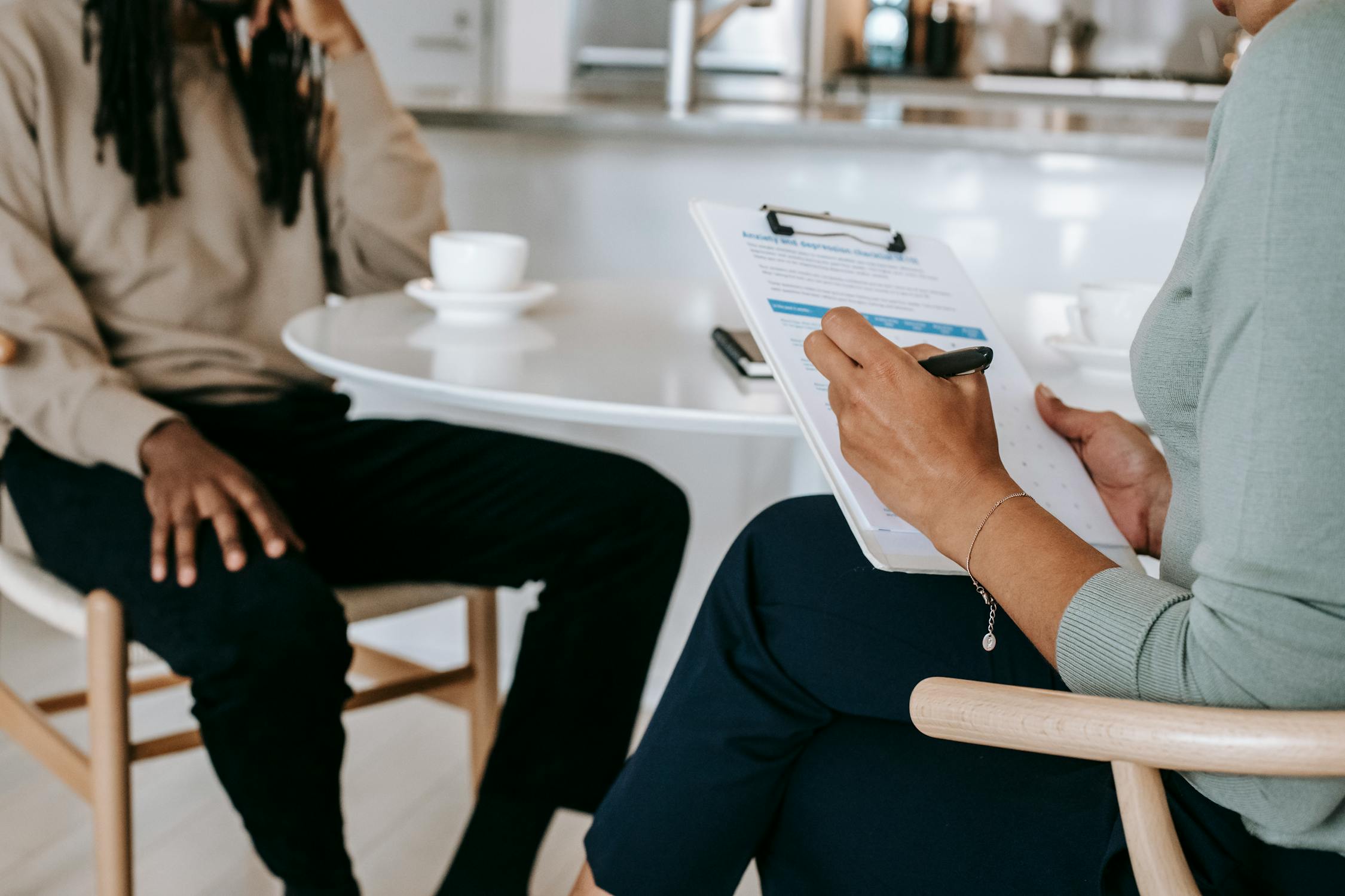 Photo of job interview, hand holding clipboard, sitting across the table from candidate