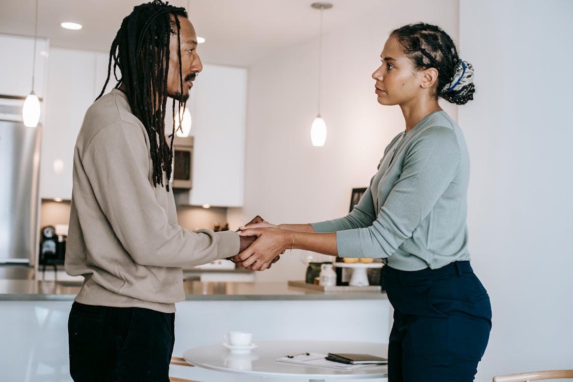 Free Side view positive multiethnic male client and female psychotherapist in formal clothes shaking hands and looking at each other after psychotherapy session in light modern studio Stock Photo