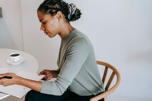 Crop ethnic woman taking notes in clipboard