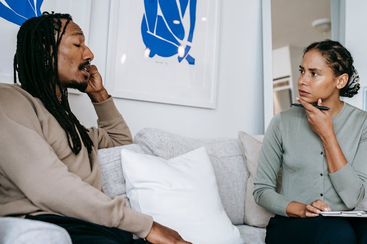 Serious ethnic female psychologist listening to black patient complaints