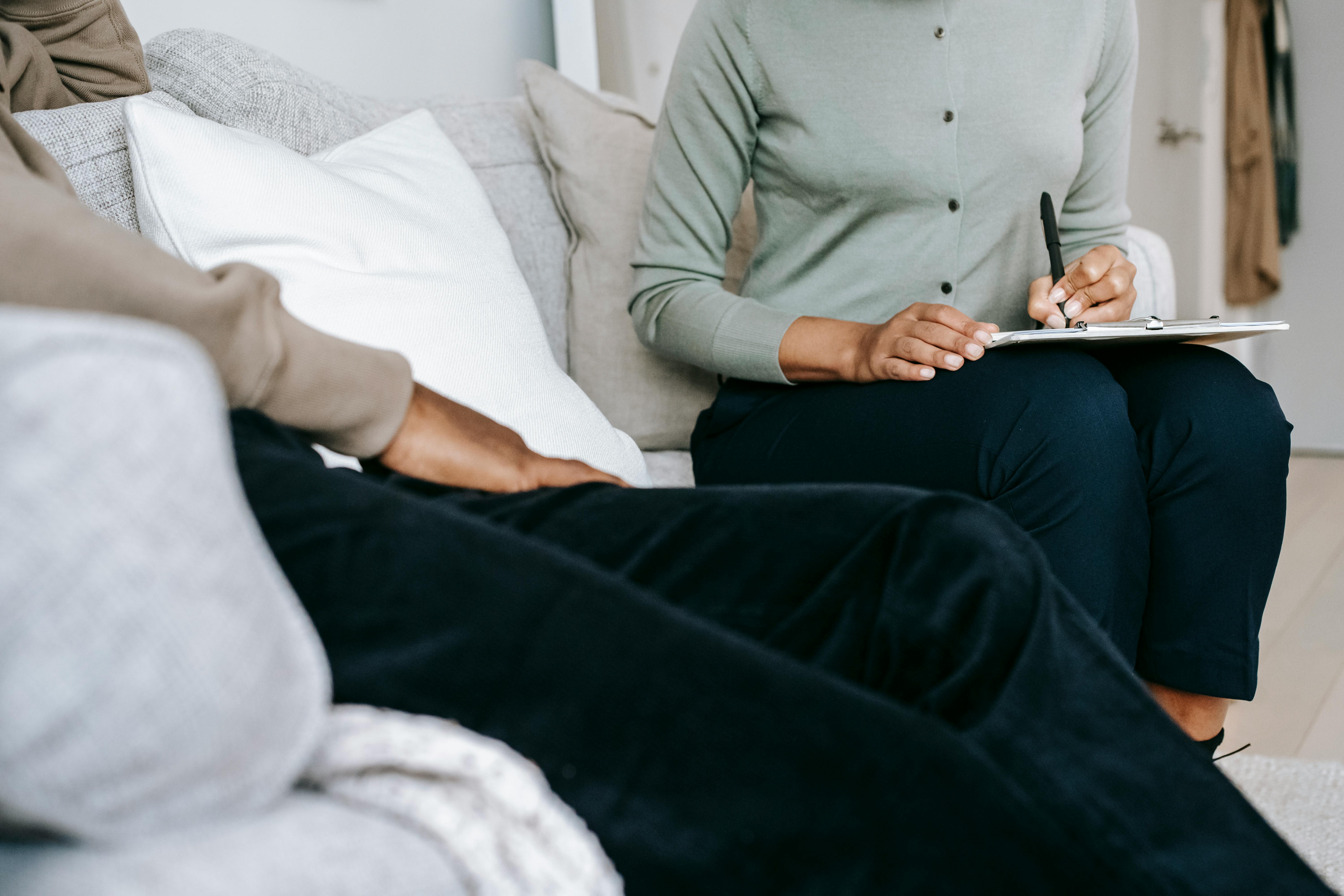 crop faceless female psychologist taking notes during psychotherapy session