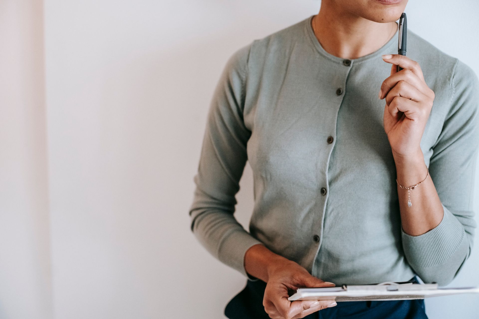 Businesswoman in thoughtful pose holding a clipboard indoors.