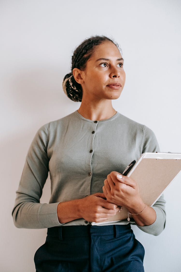 Pensive Hispanic Woman Standing With Clipboard