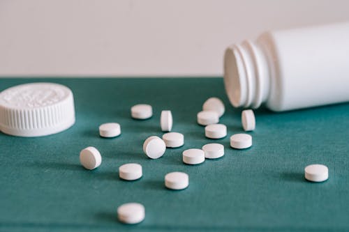 Free Pills spilled out of white jar Stock Photo