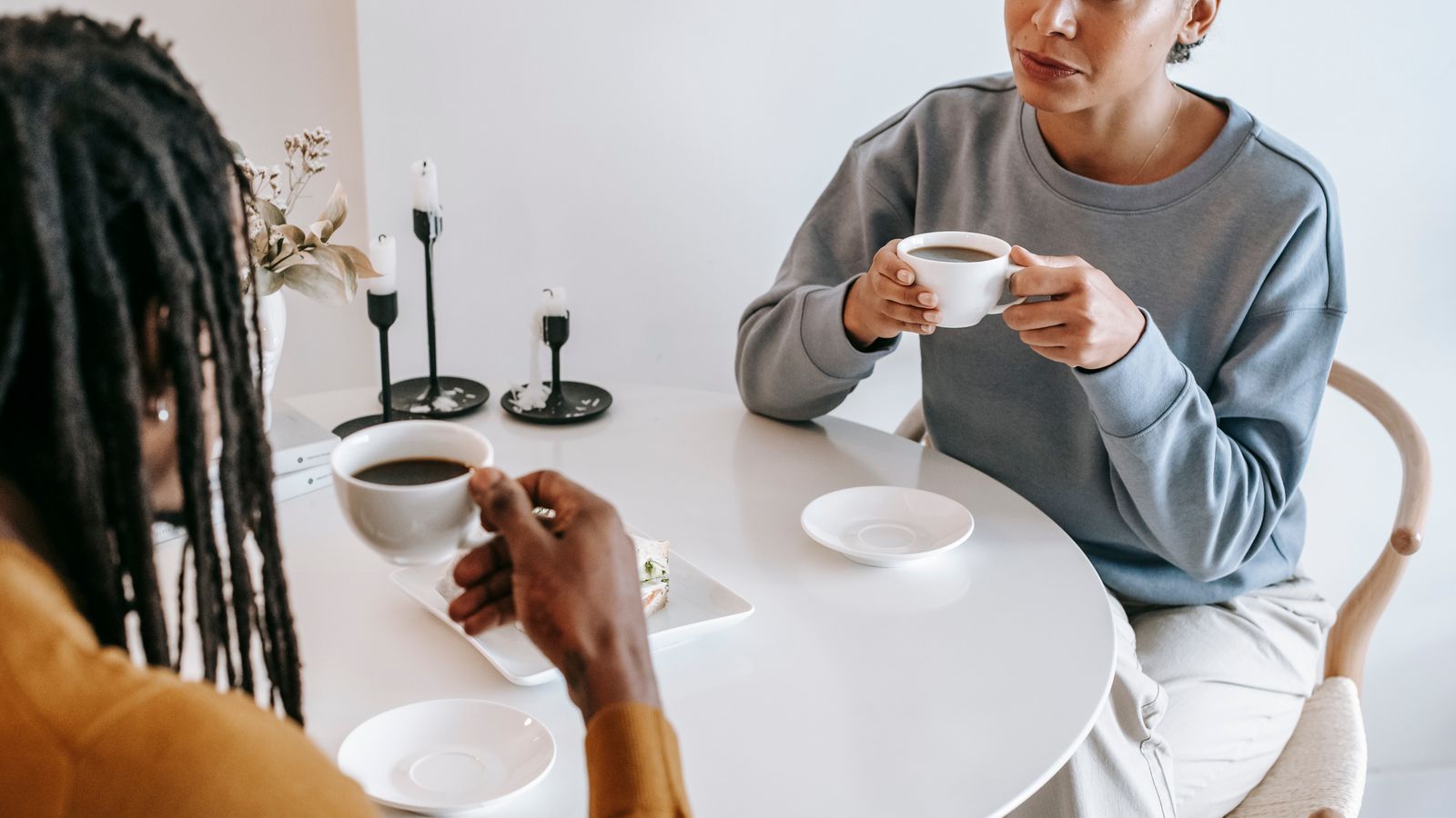 Two adults holding coffee cups at a white table