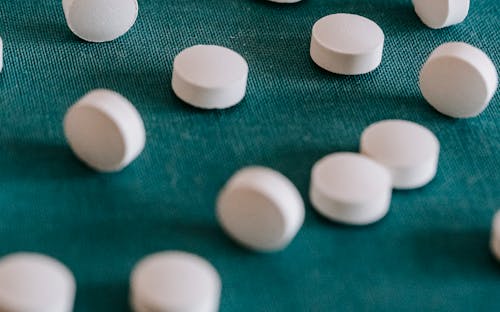Closeup of similar round white pills spilled on green tissue in random order