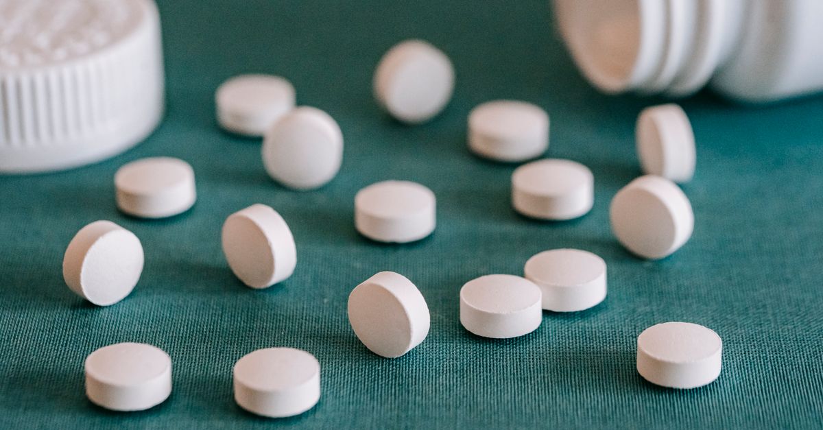 Closeup of assorted similar white round pills spilled from plastic bottle on green surface - Evidence evidence guide for Glucosamine Osteoarthritis Randomized Trial: What the Evidence Says