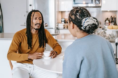 Free African American male having conversation with African American female in kitchen while having breakfast Stock Photo