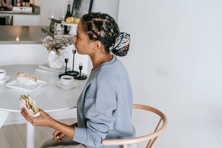 Ethnic Woman Eating Sandwich At Table