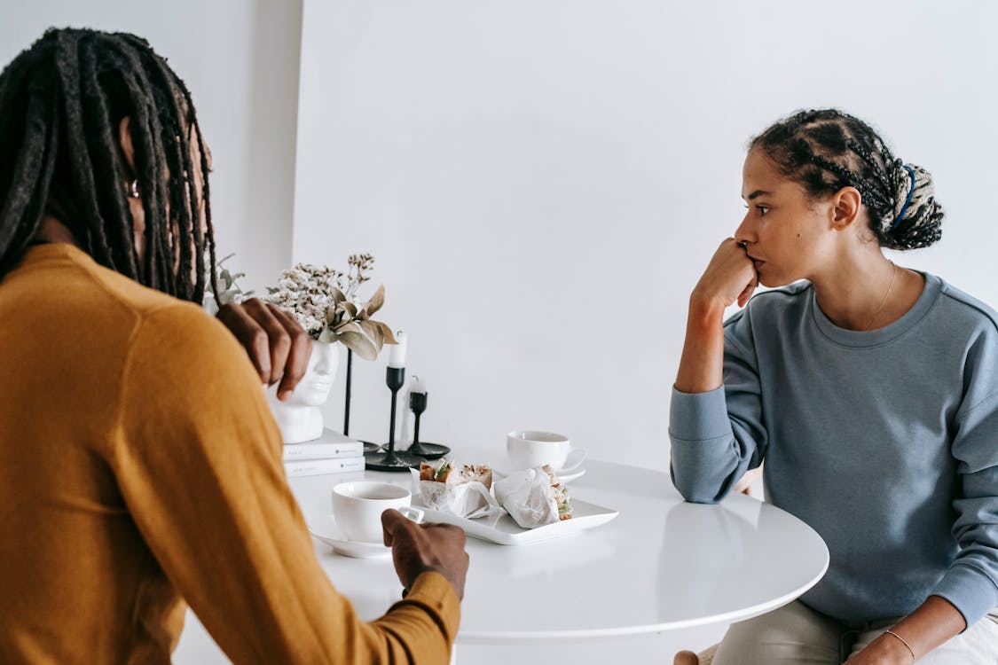 Free Young African American man sitting with woman at table and having conflict with each other at home Stock Photo