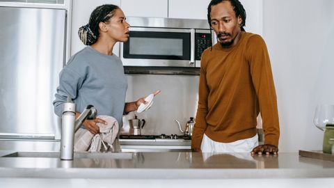 African American guy and lady in casual clothes standing and arguing in kitchen in daytime