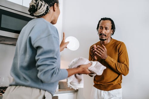 African American guy and lady standing and arguing in kitchen while wearing casual outfit in daylight