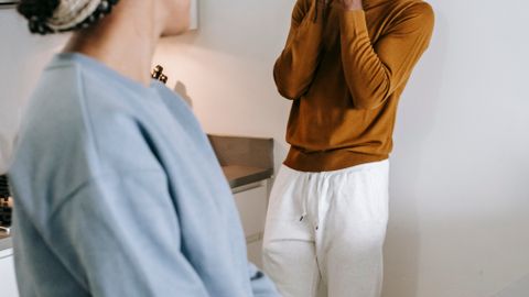 Young African American couple standing in room and arguing with each other while wearing casual clothes at home