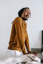 一个穿着休闲服的严肃年轻黑人站在厨房桌子旁，目光移向别处