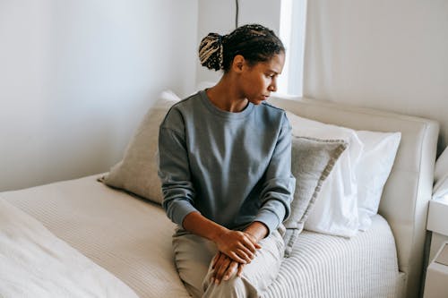 Черная женщина, сидящая на кровати у себя дома
