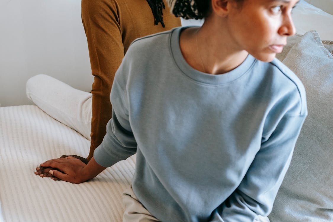 Free High angle of young black couple wearing casual clothes sitting on bed with sad face while holding hands at home in daytime Stock Photo