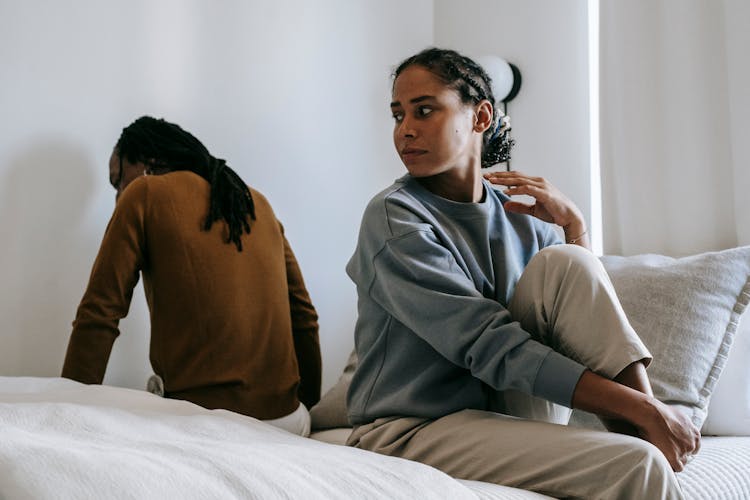 Black Couple Sitting On Bed Together